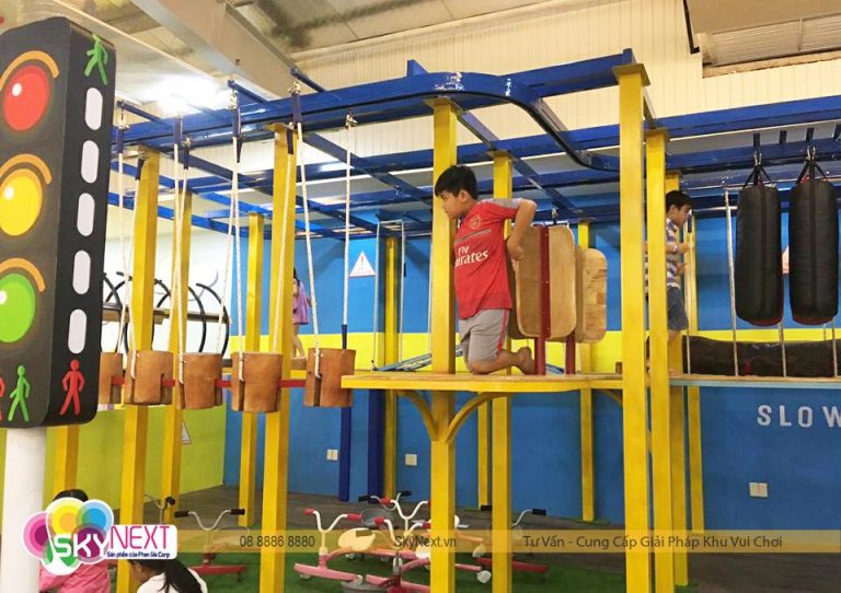 Trẻ em đang vượt chướng ngại vật trên khung cao với bậc gỗ treo và túi đấm
