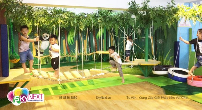 Trẻ em chơi trên cầu gỗ treo bằng dây trong khu vui chơi trong nhà