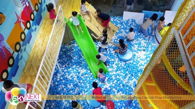 Trẻ em chơi trong hồ bóng xanh trắng với cầu trượt xanh