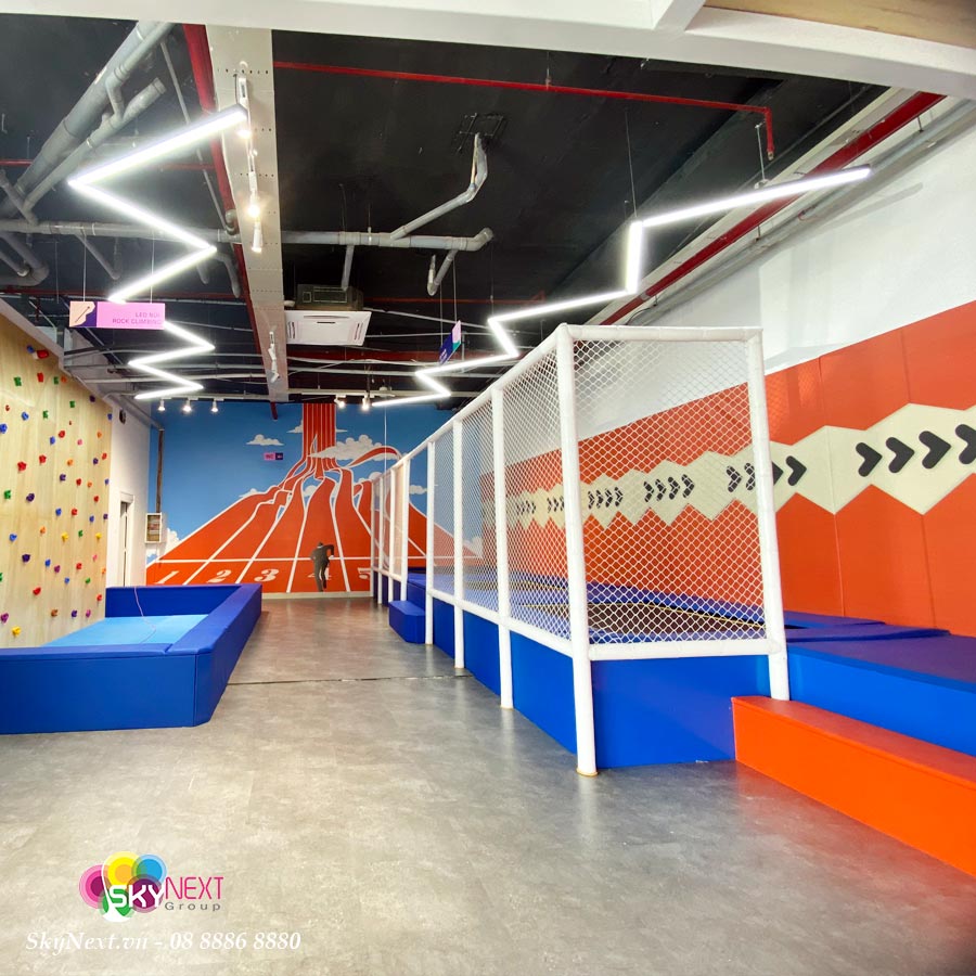 Khu vui chơi trẻ em trong nhà với đệm xanh cam, vách leo núi và lưới bảo vệ